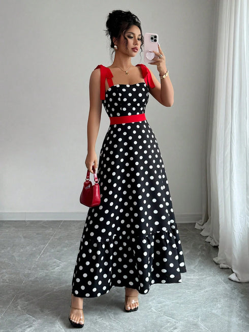 Woman taking a mirror selfie wearing a black polka dot dress with red accents.