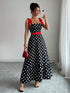 Woman taking a mirror selfie wearing a black polka dot dress with red accents.