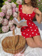 Woman in a red polka dot dress reading a book with a picnic basket next to her, surrounded by pink flowers.