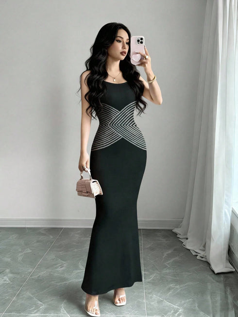 Woman taking a mirror selfie wearing a black and gray dress in a room with gray walls and white curtains.