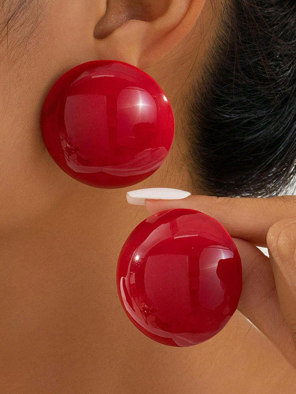 Close-up of a person wearing large red spherical earrings.