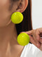 Close-up of a person wearing bright green earrings with a plain background