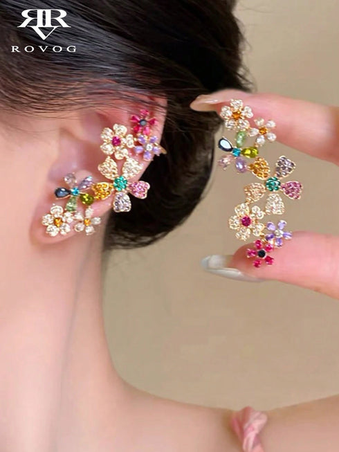 Colorful floral earrings being worn and held up to a person's ear, with 'ROVOG' branding visible.