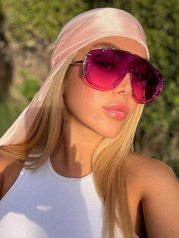 Person wearing a visor and pink sunglasses with a blurred natural background
