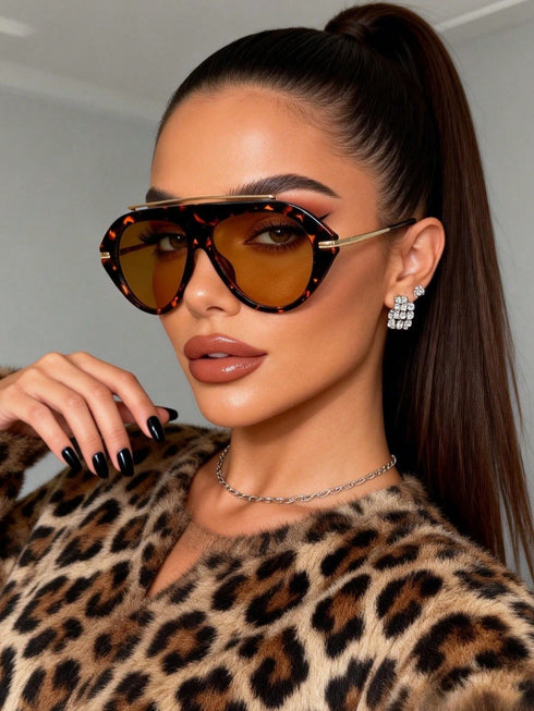 Woman wearing leopard print sunglasses and coat with a neutral background