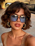 Woman wearing sunglasses and large hoop earrings with a blurred background
