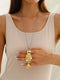 Woman wearing a gold fish-shaped pendant necklace and ring against a neutral background