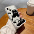 Phone case with a black and white cat design held by a person on a wooden table.
