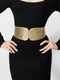 Person wearing a black dress with a gold belt on a white background
