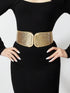 Person wearing a black dress with a gold belt on a white background