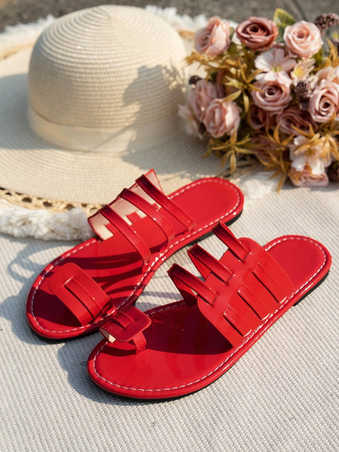 Red sandals on a textured surface with a straw hat and flowers in the background