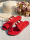 Red sandals on a textured surface with a straw hat and flowers in the background