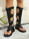 Black lace-up sandals worn by a person on a neutral background