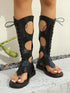 Black lace-up sandals worn by a person on a neutral background
