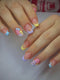 Close-up of a person's hands showcasing a pastel French manicure with floral nail art designs in pink, yellow, blue, and purple.