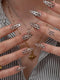 Close-up of hands with decorative nails and necklaces against a striped background