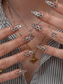 Close-up of hands with decorative nails and necklaces against a striped background