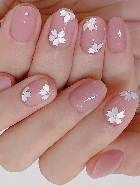 Nails with pink polish and white floral designs on a neutral background