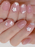 Nails with pink polish and white floral designs on a neutral background