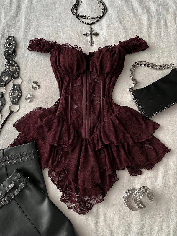 A dark burgundy lace corset top with ruffled off-the-shoulder straps and layered ruffles, styled in a flat lay with black leather pants, silver chain accessories, and a black studded handbag on a white textured fabric background.