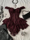 A dark burgundy lace corset top with ruffled off-the-shoulder straps and layered ruffles, styled in a flat lay with black leather pants, silver chain accessories, and a black studded handbag on a white textured fabric background.