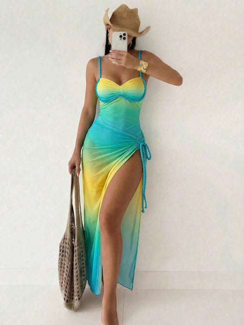 A woman takes a mirror selfie wearing a sleeveless gradient maxi dress with a yellow-to-blue color transition, a cowboy hat, and holding a woven tote bag.