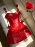 A bright red strapless mini dress with 3D rose embellishments on the straps, bodice, and skirt, displayed on a cream-colored leather sofa. A circular inset in the top right shows a close-up of the red rose detail with the text '3D flower'.