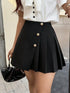 Person wearing a black pleated skirt with gold buttons and a white blouse.