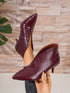 Burgundy crocodile-patterned high heels on a neutral background