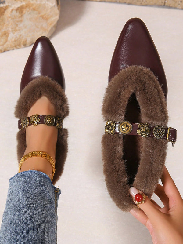 A pair of pointed-toe flats with brown faux-fur trim and an ornate gold-tone ankle strap, shown on a foot and held separately against a light neutral background.