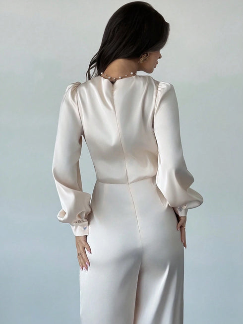 Woman wearing a white satin dress with long sleeves against a plain background