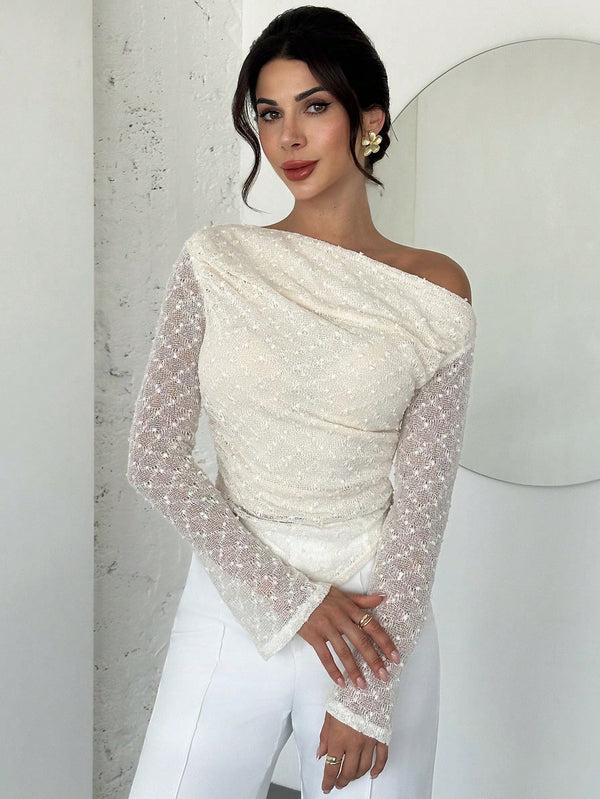 Woman wearing a white off-shoulder top with sheer sleeves against a light background