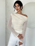 Woman wearing a white off-shoulder top with sheer sleeves against a light background