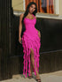 Woman wearing a bright pink dress with ruffled layers standing outdoors.