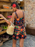 Woman in a floral dress holding a straw bag in a market setting