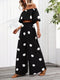 Woman wearing a black off-shoulder top and wide-leg pants with white polka dots, standing indoors.