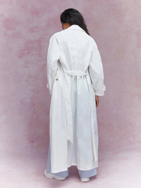 Person wearing a long white coat against a pink background