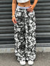Person wearing camouflage pants and white sneakers standing in front of a metallic shutter.