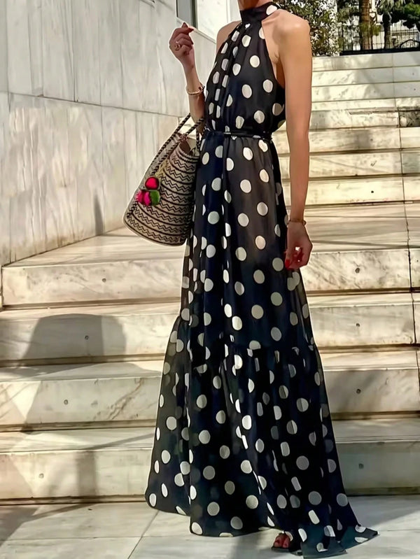 Woman wearing a black polka dot dress standing on stone steps.