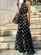 Woman wearing a black polka dot dress standing on stone steps.