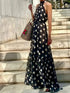 Woman wearing a black polka dot dress standing on stone steps.