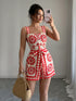 Woman taking a mirror selfie wearing a red and white floral dress.