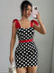 Woman taking a mirror selfie wearing a black polka dot dress with red accents.