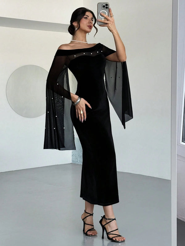 A woman takes a mirror selfie wearing a black off-the-shoulder midi dress with sheer flutter sleeves adorned with small silver studs, paired with black strappy high-heeled sandals.