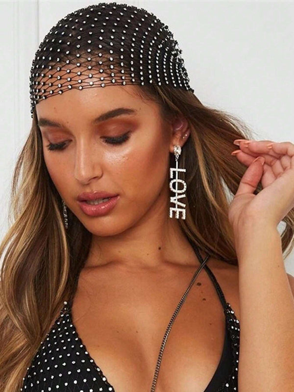 Woman wearing a black beaded headpiece and 'LOVE' earrings against a white background