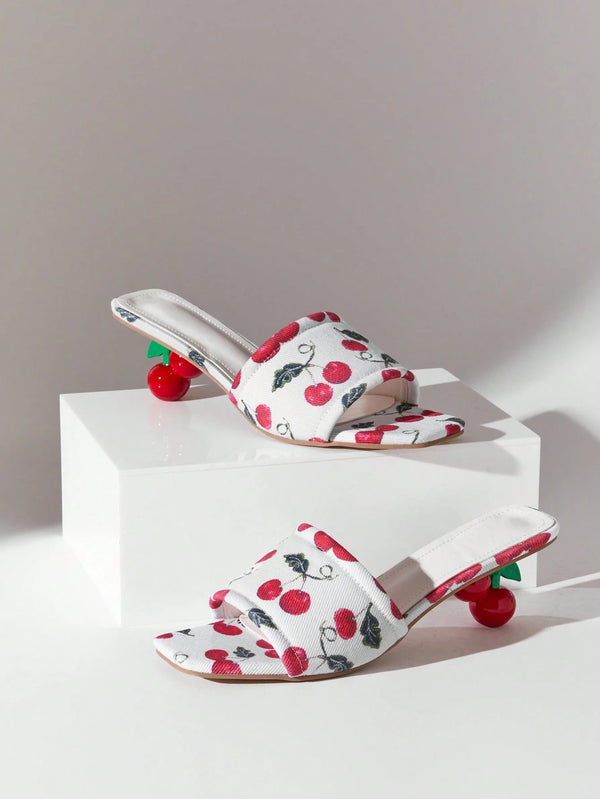 Pair of white sandals with red cherry pattern on a white platform against a gray background