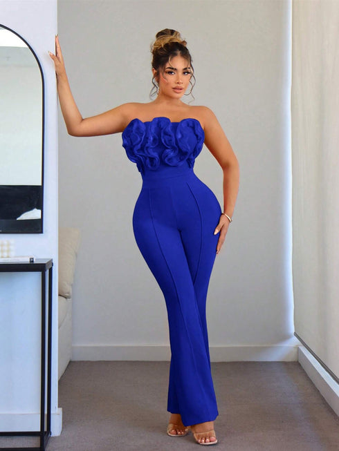 Woman wearing a blue strapless jumpsuit with floral details in a room.
