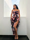 Woman wearing a strapless floral dress with a high-low hem in a minimal indoor setting.