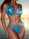 Woman wearing a blue bikini with floral design against a beach background
