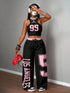 Person wearing a black and pink 'Los Angeles' outfit with headphones and a red bag.